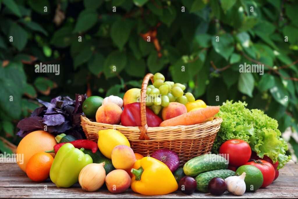 heap of fresh fruits and vegetables in basket on table outdoors 2bj25ty